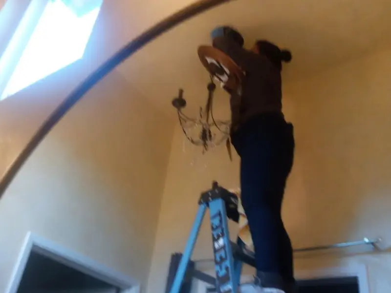 Electrician installing a chandelier in a Upper Dublin residence